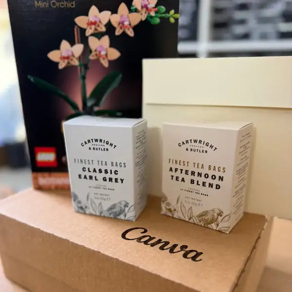 A LEGO orchid set with two boxes of tea and a cream envelope, on a branded kraft box